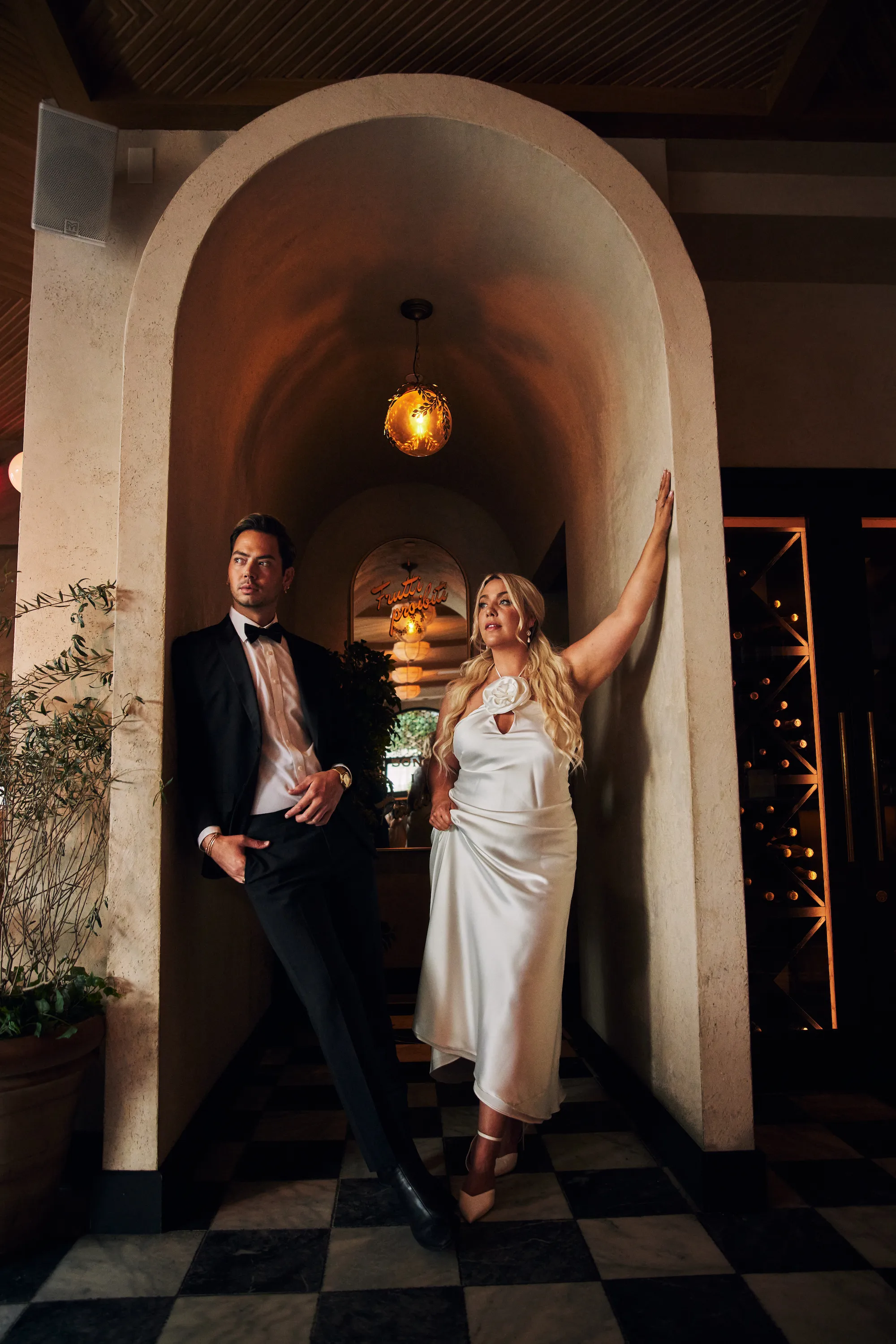 engagement photo outfits at a restaurant or hotel engagement session, couple in formal gown and suit standing in a warmly lit arched stone doorway