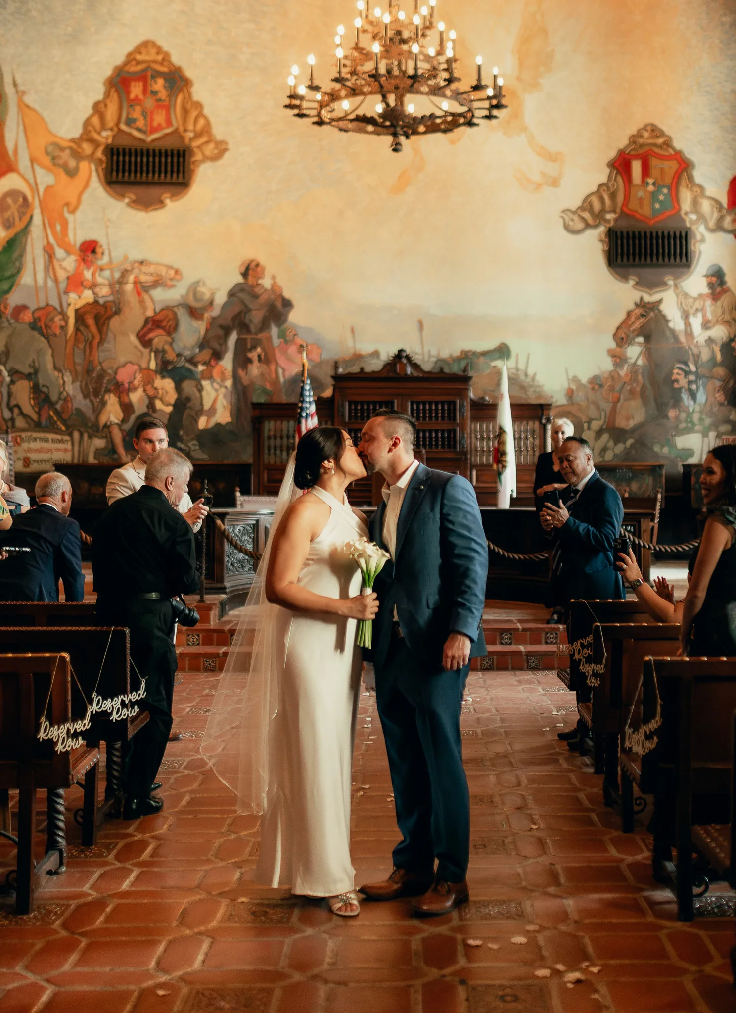Couple exchanging vows inside the Mural Room at the Santa Barbara Courthouse with the historic painted murals filling the wall behind them