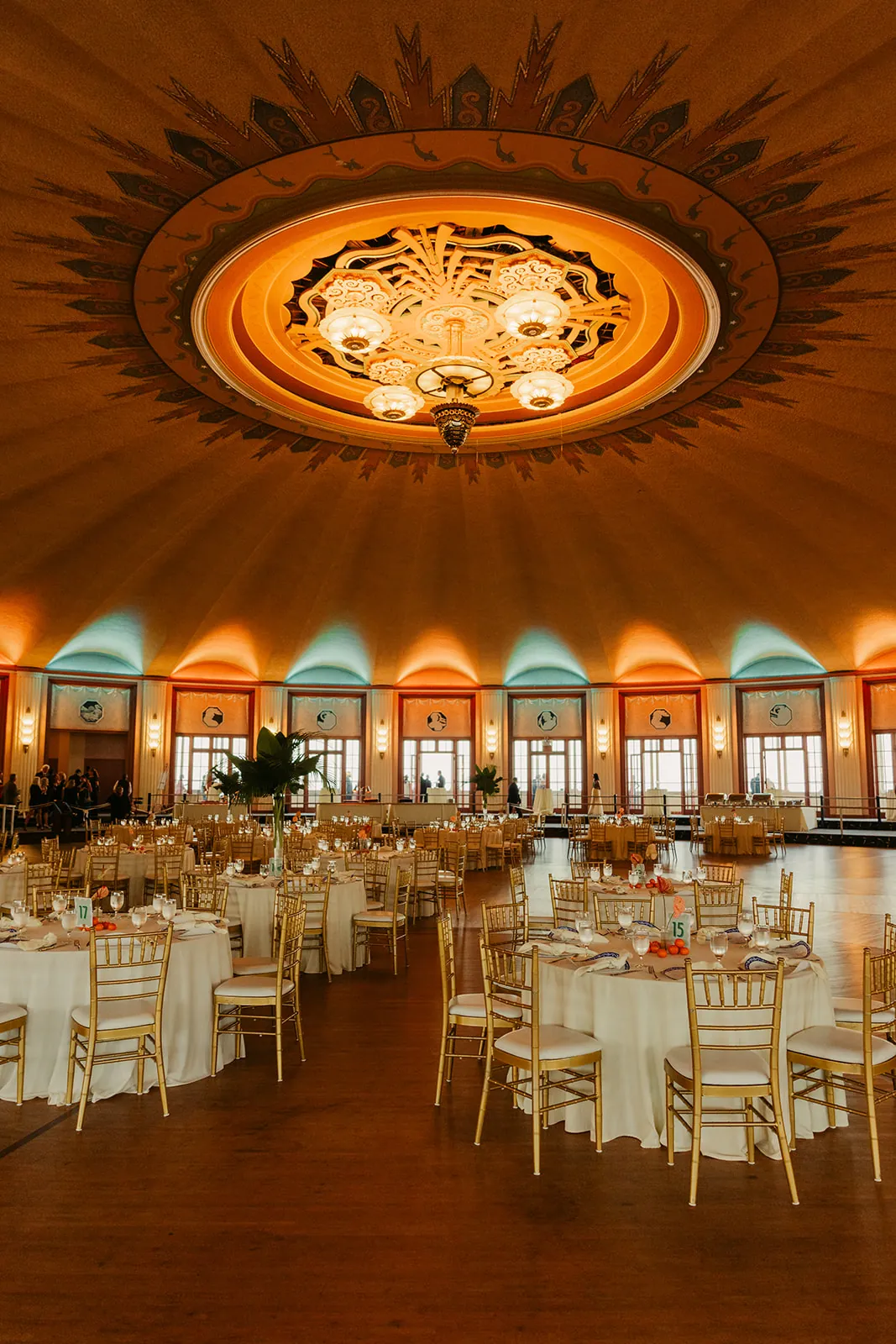 Catalina Island Casino Ballroom wedding reception setup shot from below the art deco ceiling medallion, showing the full circular room with round tables and warm uplighting