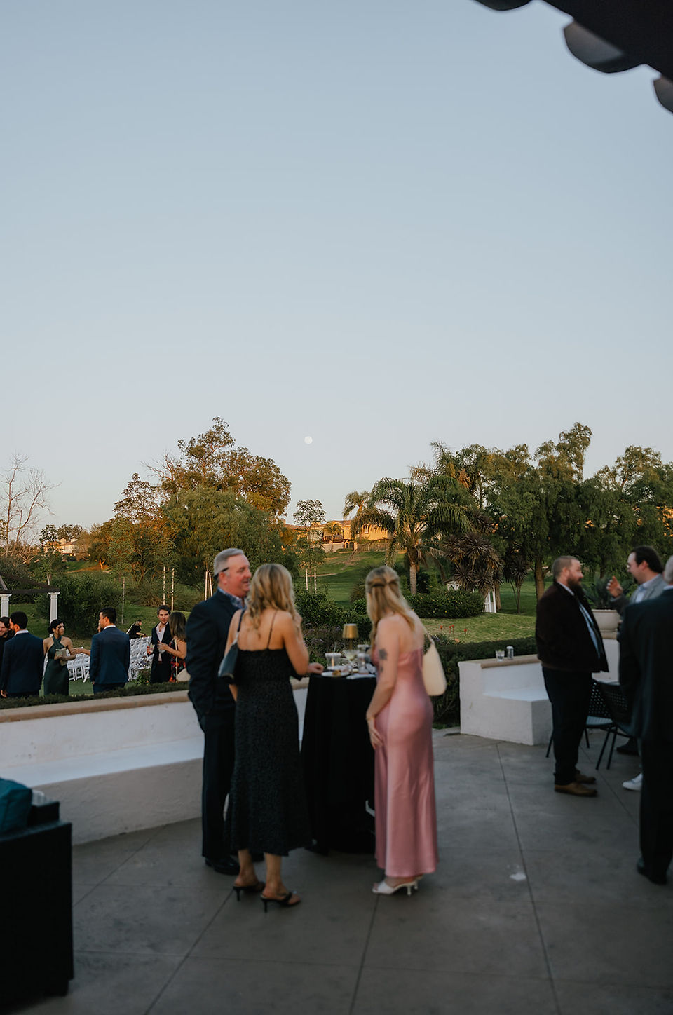 Wedding guests gather on the patio as the moon rises during cocktail hour at Sterling Hills.