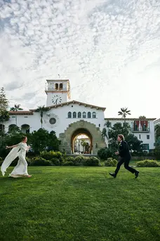 Bride running across the Sunken Gardens lawn toward groom at the Santa Barbara courthouse