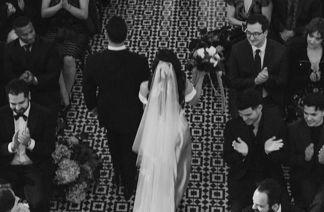 Black and white overhead photo of bride and groom walking down the aisle past their guests.