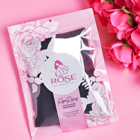 A confident mother holding her newborn while wearing comfortable postpartum recovery wear, standing in soft natural light. The scene conveys strength, healing, and dignity, reflecting modern, inclusive postpartum care.