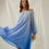 Thumbnail: Woman swishing the blue ombré Bernadette Dress as it flows freely, not tied at all.