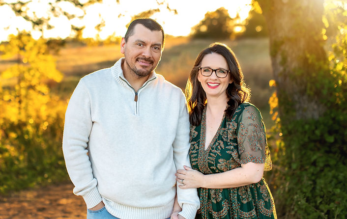 Adrian Chavez, founder of Chavez Coaching Strategies, smiling with his wife Jen in an outdoor family photo