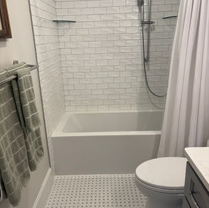 Modern bathroom with subway tile shower and white tub.