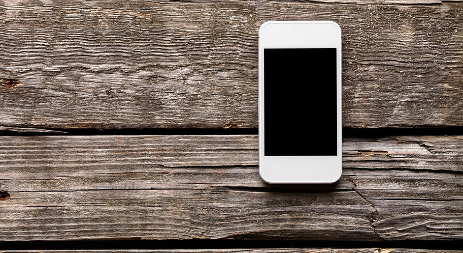 White smart phone with isolated screen on old wooden desk..jpg