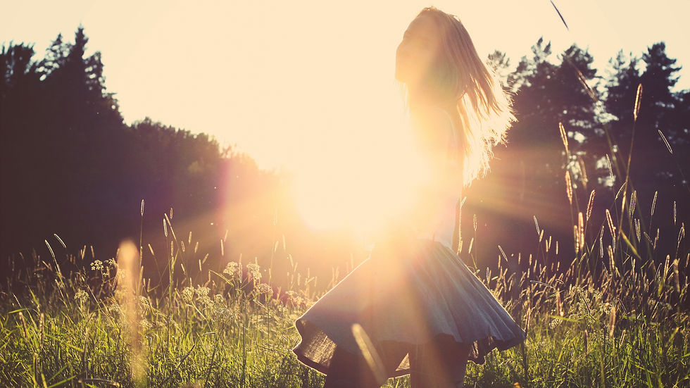 A happy woman, dancing in the field at sunset