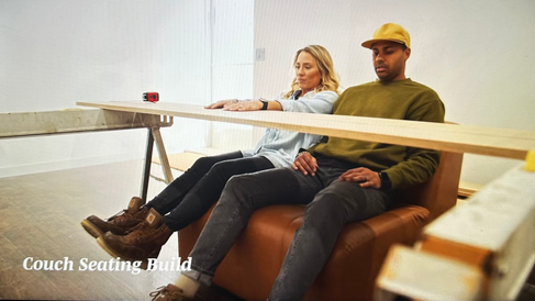 Couple sitting on couch discussing plans for table.