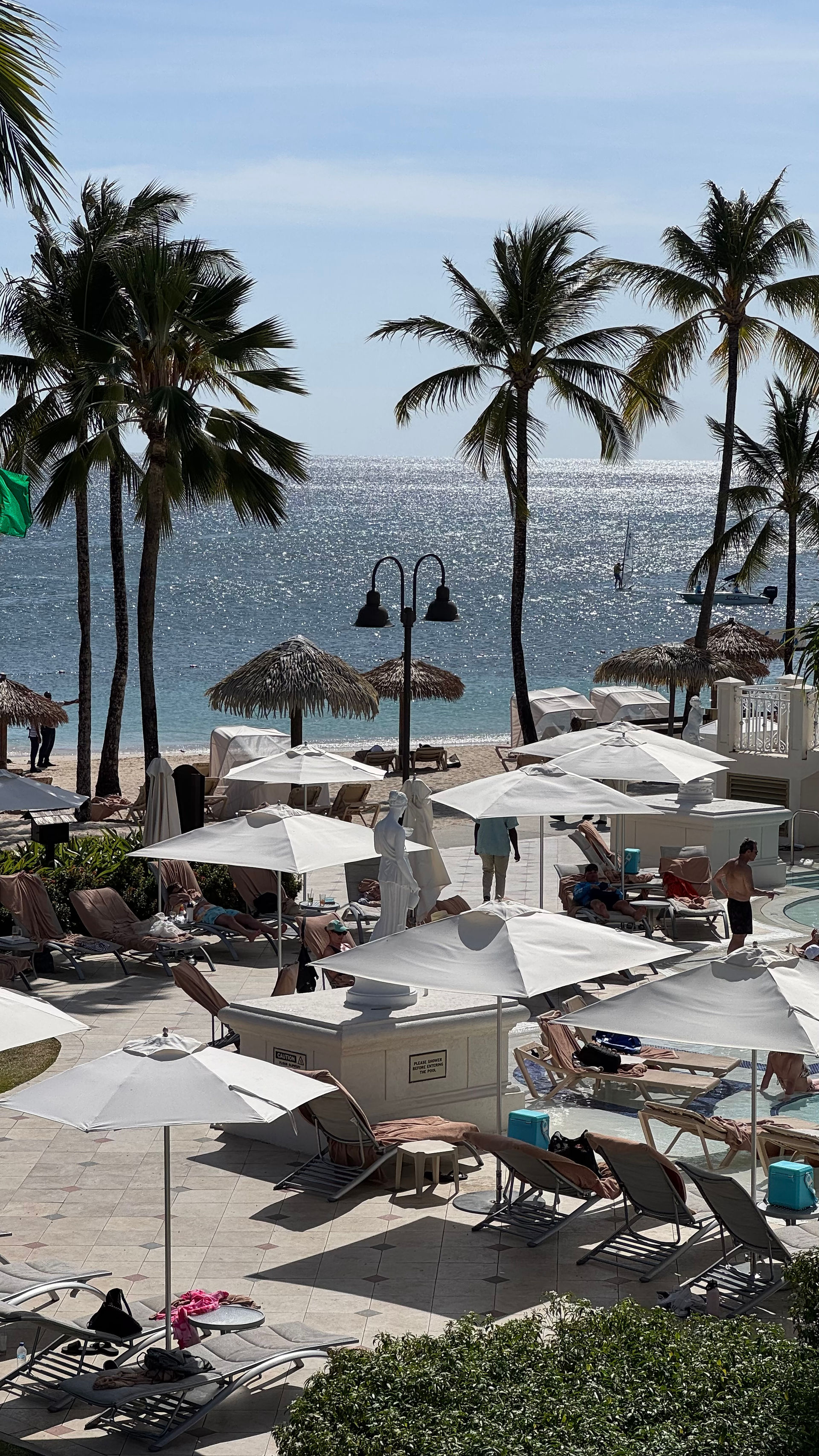 tropical beach resort setting with umbrellas in the sand surrounded by lush palm trees