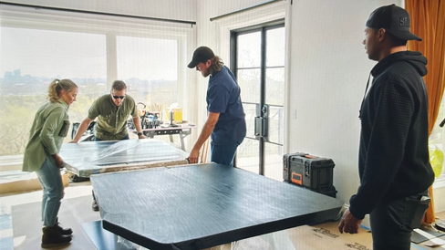 Team of four working to piece together a large dining table.