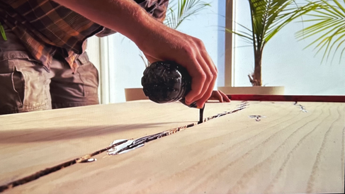 Man pours epoxy resin into wood slab.