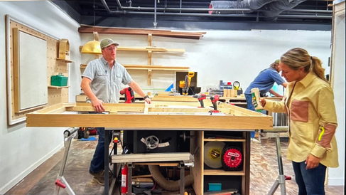 Team of people working on wood project in a workshop setting.