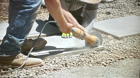man using grinder to saw through concrete paver