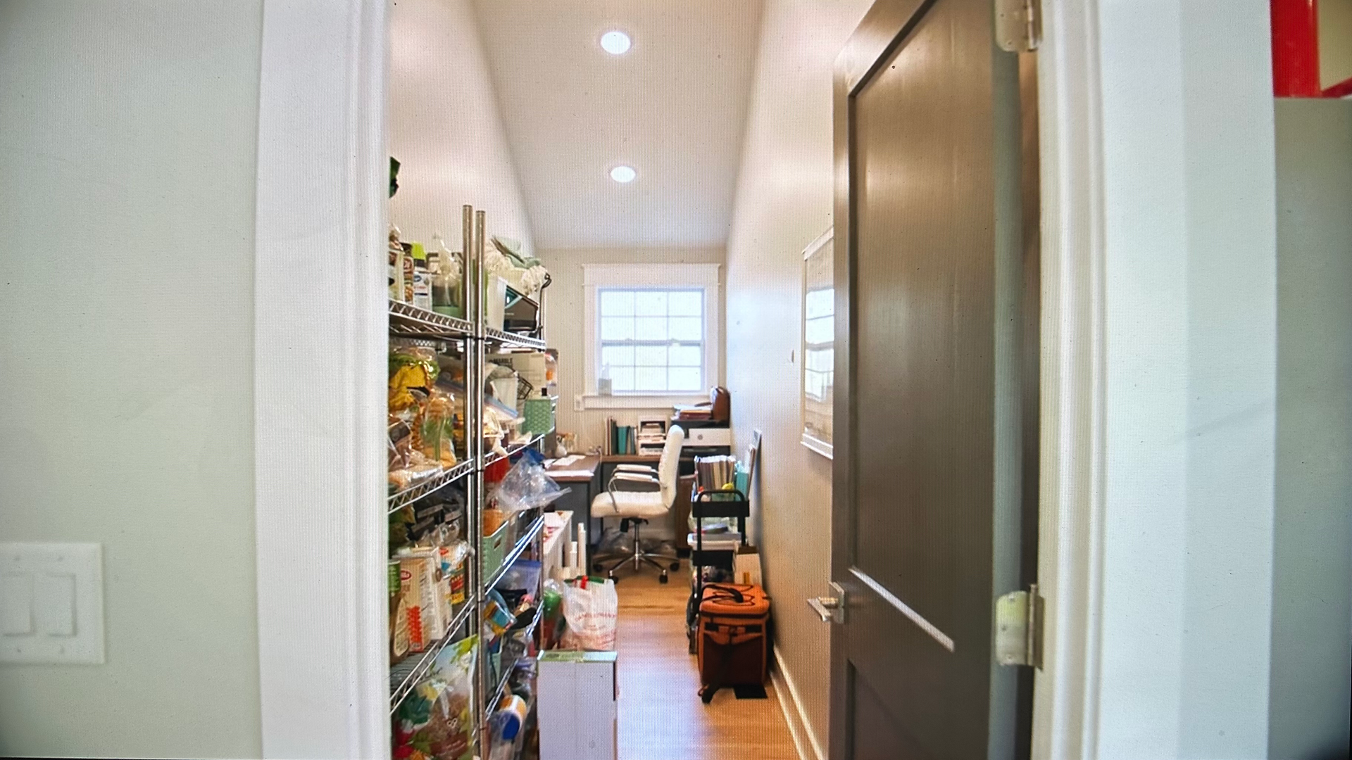 long narrow pantry with food and miscellaneous items on metal shelving