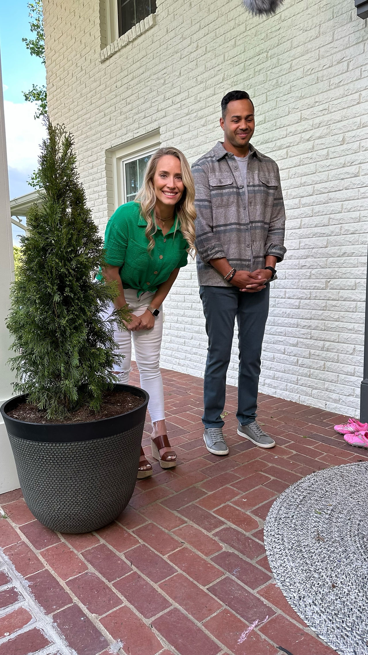 woman looking at camera and smiling with man beside her on a brick porch