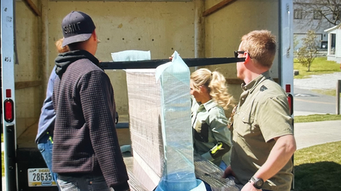 Team of four unloading large piece of furniture from moving truck.