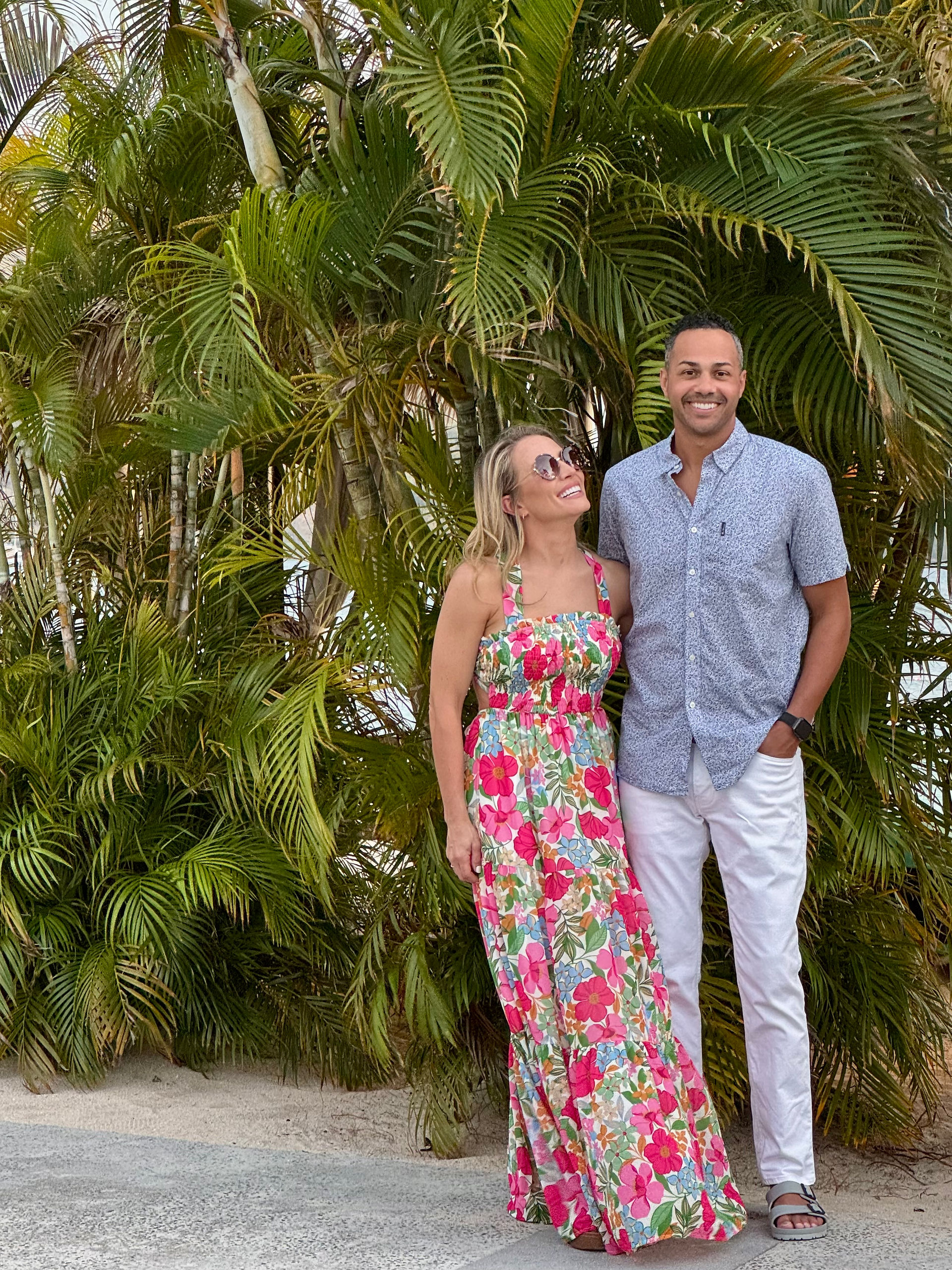 two people stand among palm trees