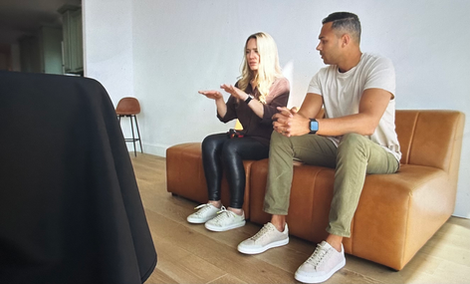 couple sits on small sofa while appearing to discuss something