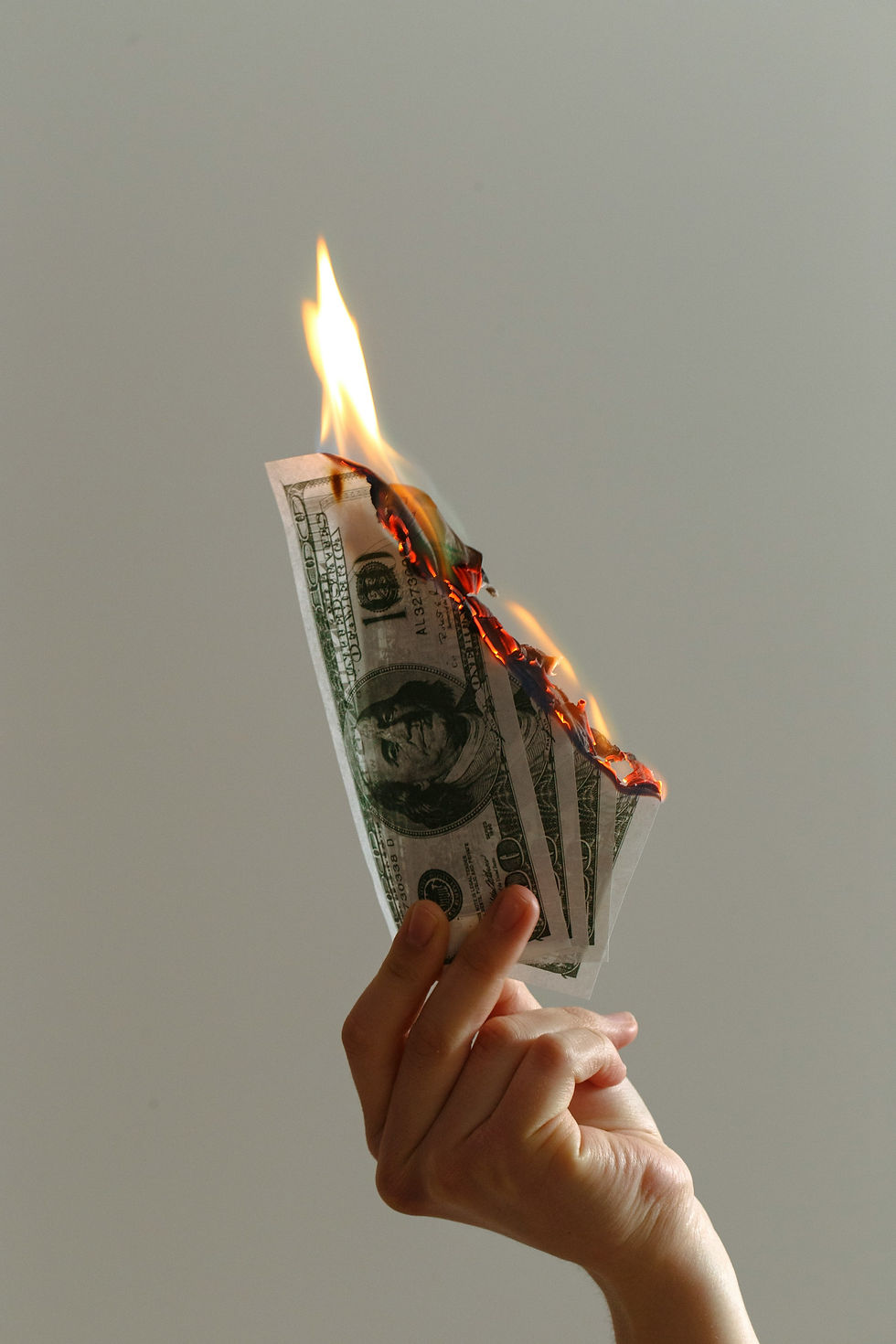 person holding lighted dollar bills on fire