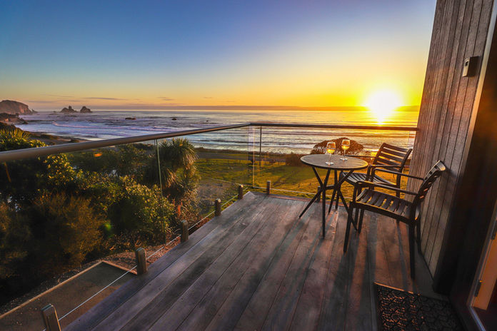 Sunset over the Tasman Sea with Motukiekie sea stacks, viewed from the private deck at View With A Room.