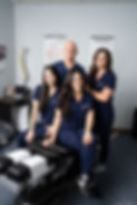 Chiropractic team in blue scrubs poses together Our Practice EHC