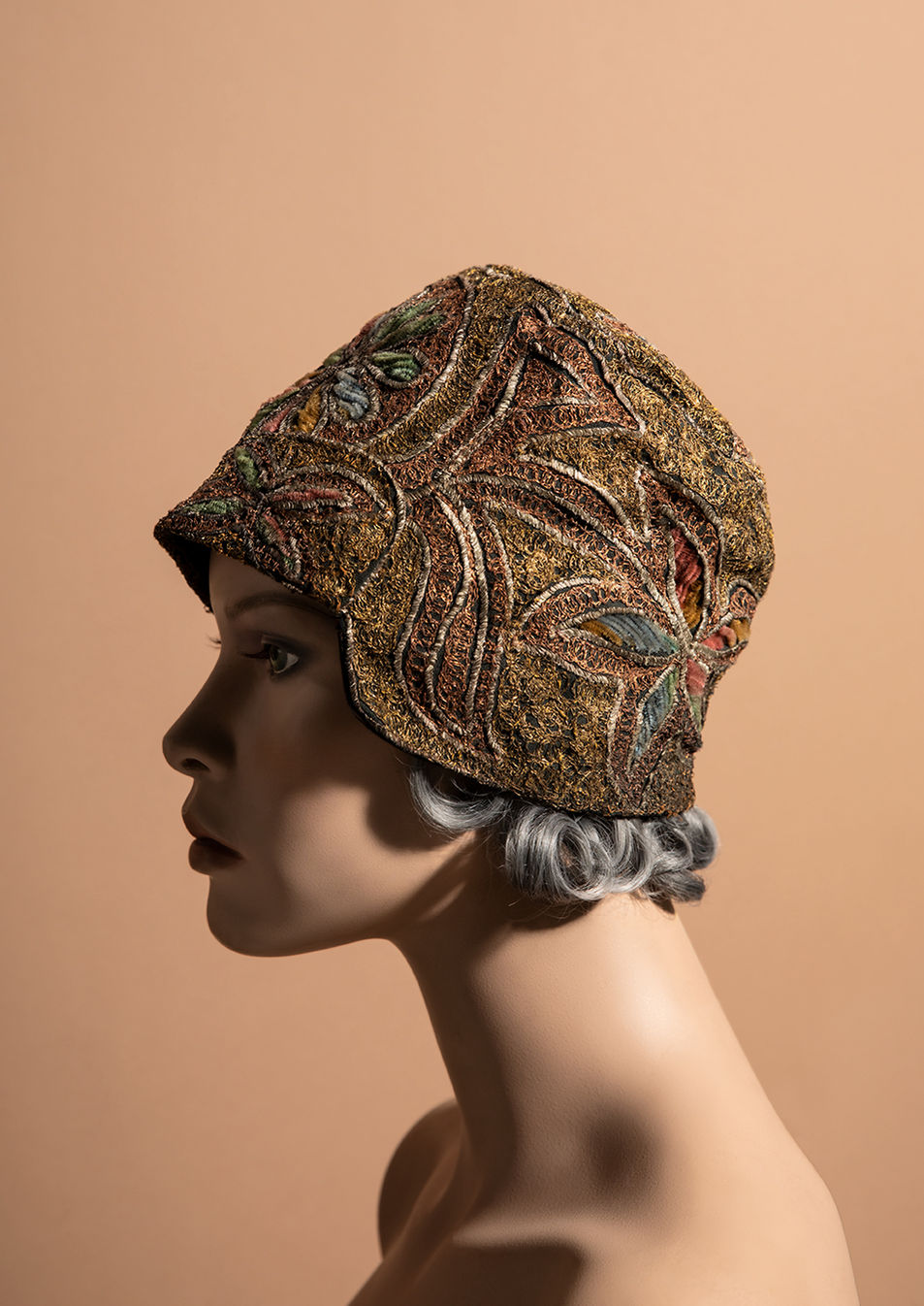 Mannequin wearing a vintage, gold, floral embroidered cloche hat