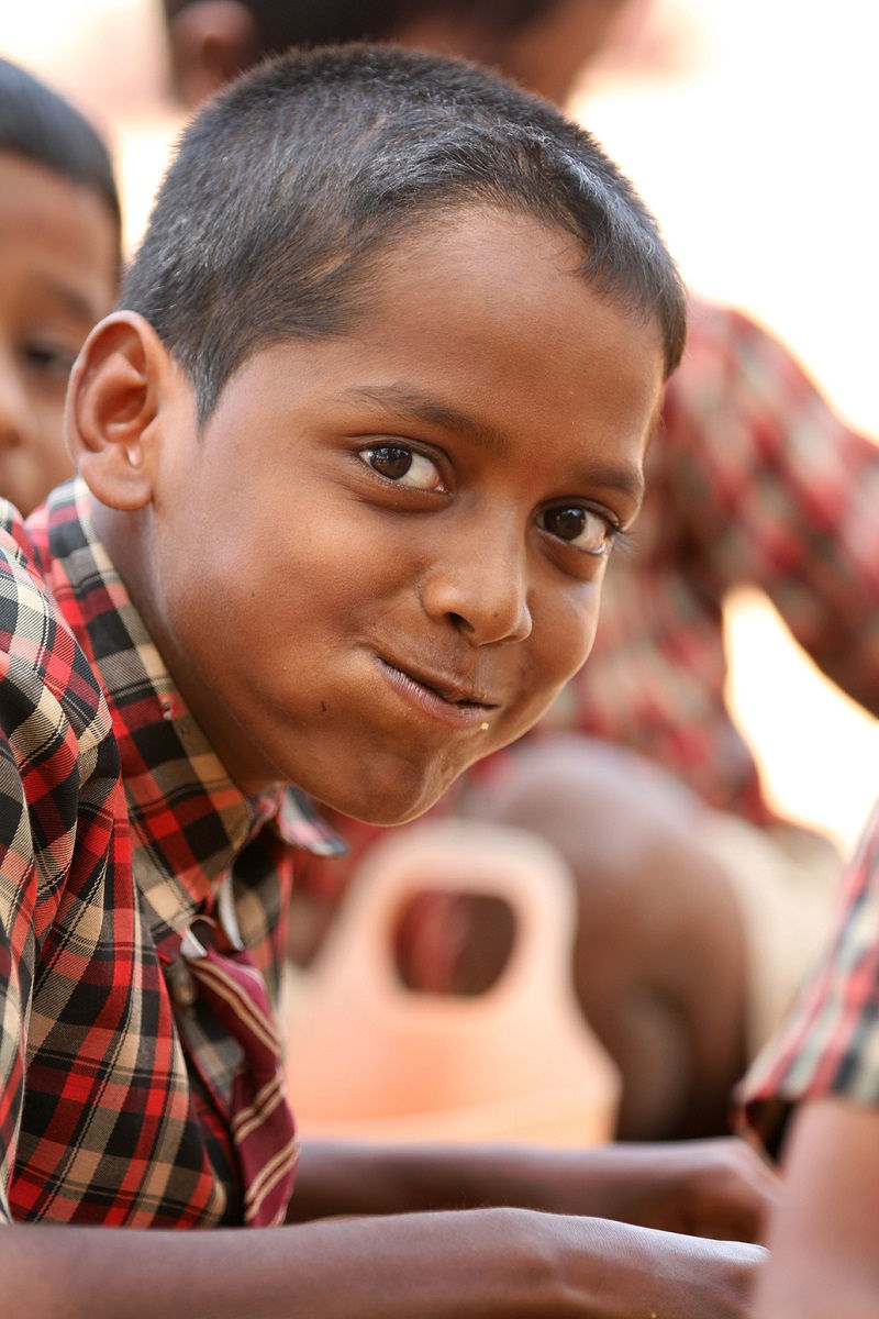 Smiling boy in plaid shirt looks directly at the camera.