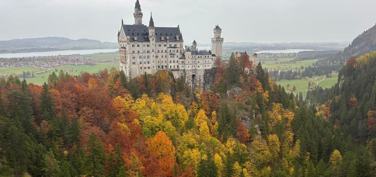 Замок Нойшванштайн на тлі безкрайніх долин та озер баварського регіону Альгой.