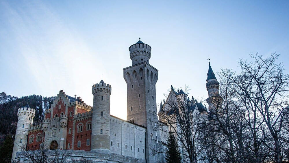 Вид на високі кам'яні вежі, дахи та мури замку Нойшванштайн зблизу.