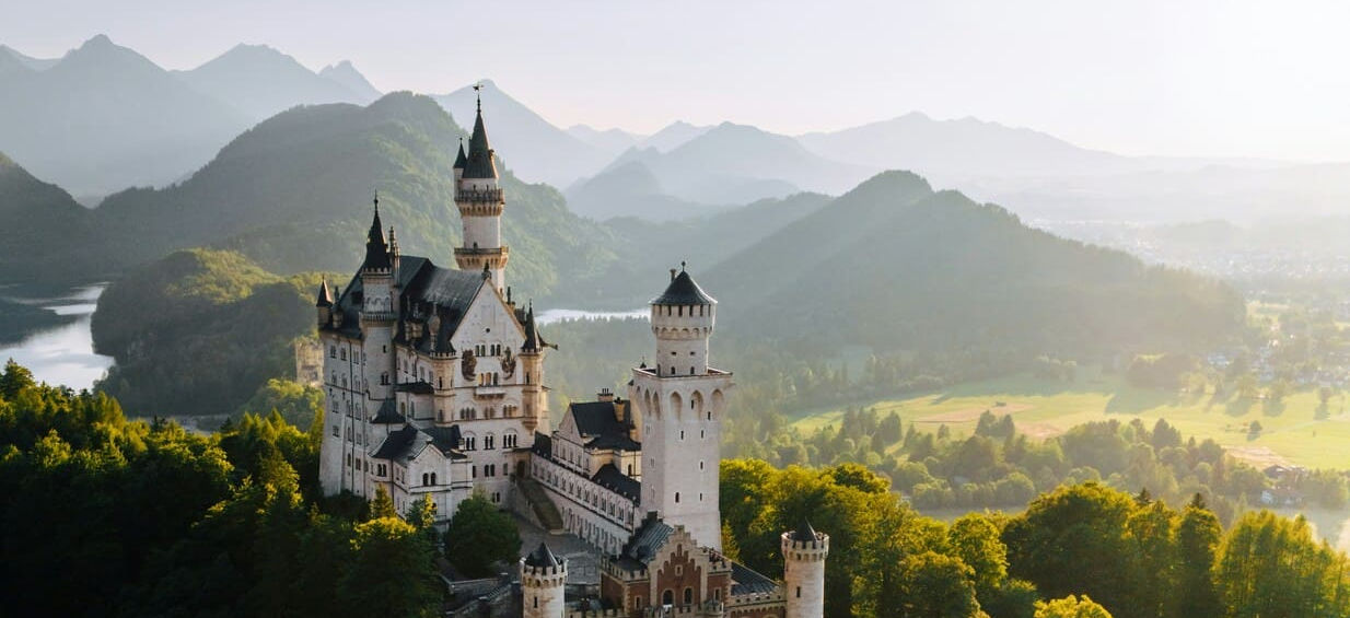 Густий ліс та високі скелясті гори Баварських Альп поблизу замку Нойшванштайн.