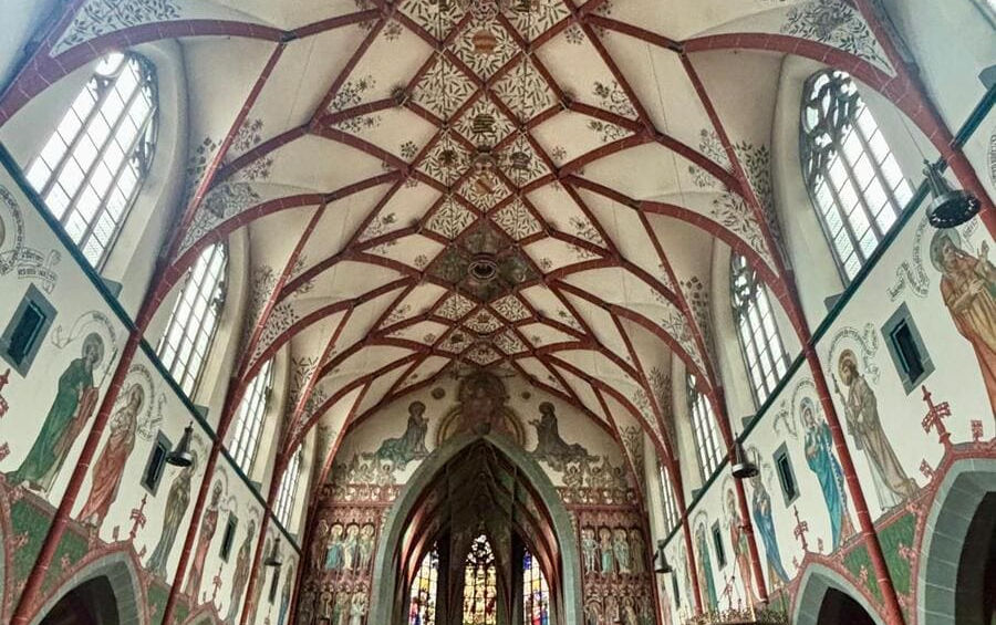 Внутрішнє оздоблення готичної церкви в Ульмі з високими склепіннями, прикрашеними геометричними орнаментами та фресками.