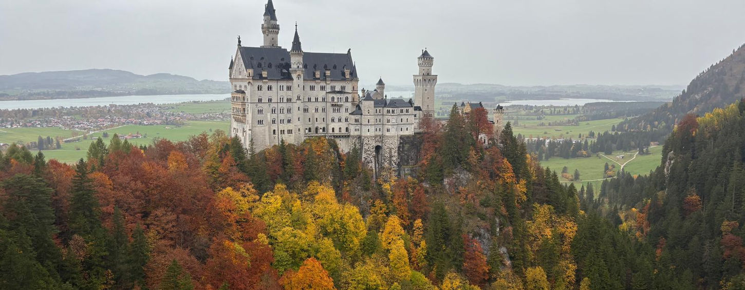 Кам'яний фасад замку Нойшванштайн з арковими вікнами та різьбленим балконом.