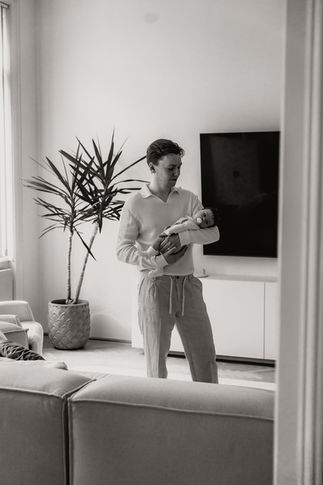 Familienfotos zuhause in Niederösterreich – Eltern kuscheln mit Baby im Wohnzimmer