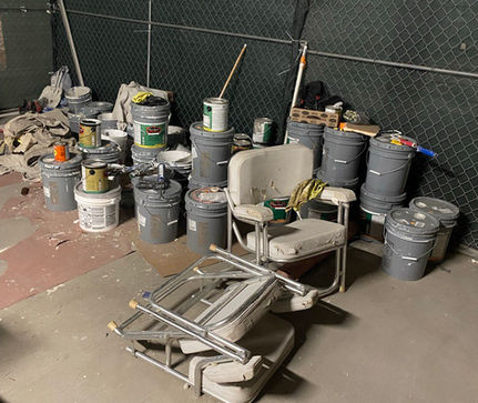 Golden Bear Hauling and Junk Removal team loading empty paint cans from a residential property into their truck for proper disposal.
