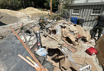Golden Bear Hauling and Junk Removal team loading construction debris like concrete and wood into a truck at a jobsite.