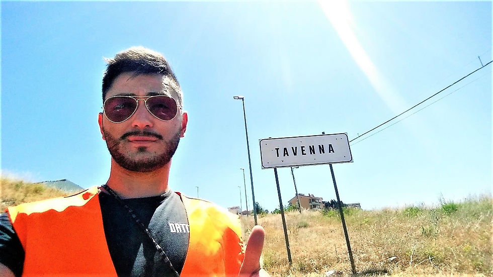 il blogger molisano Molise On The Road con alle spalle il cartello stradale di Tavenna