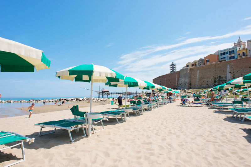 Stabilimento Balneare Cala Sveva Beach Club, con ombrelloni spiaggia , sfondo castello svevo nel periodo estivo.