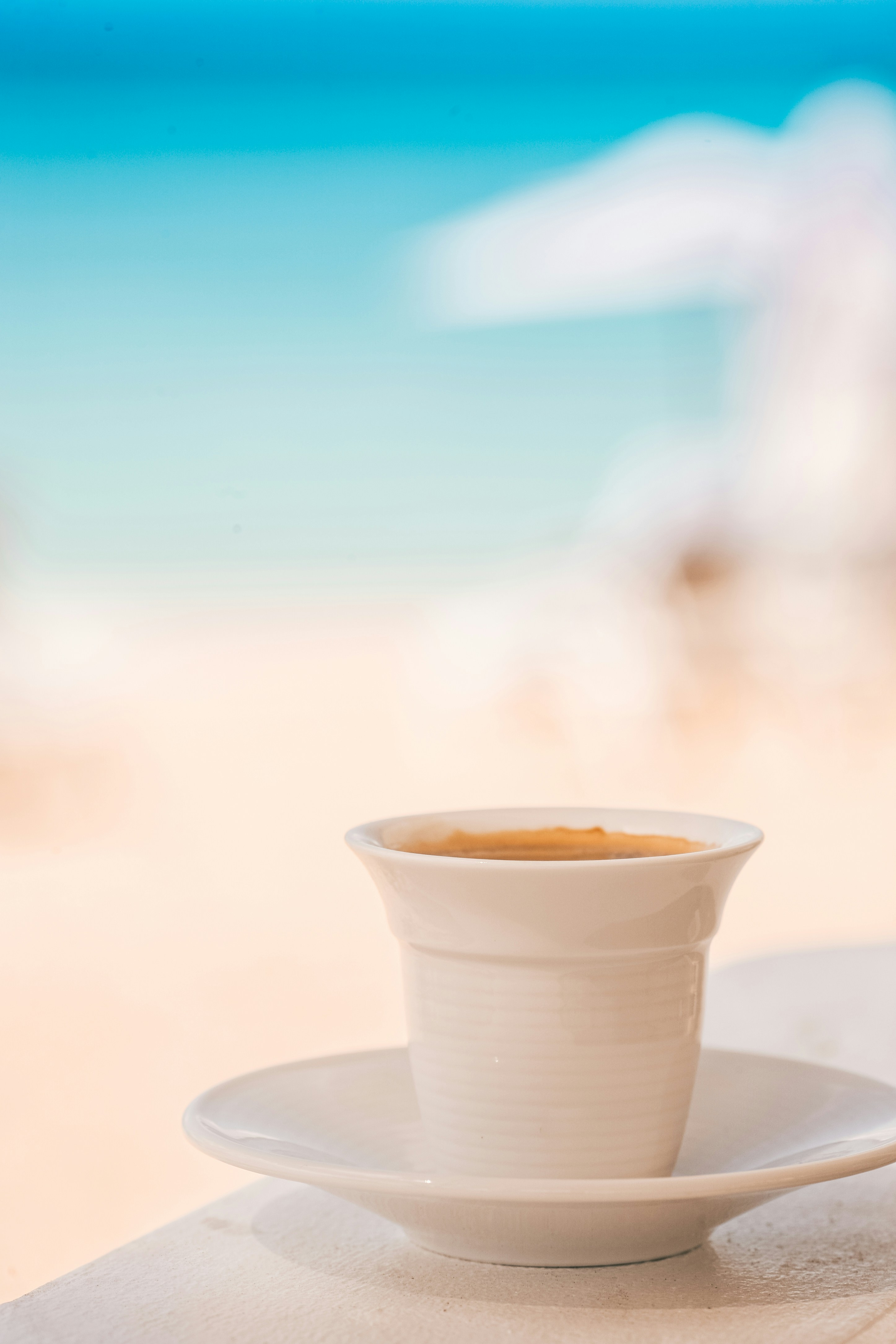 steaming cup of coffee on counter with luxury beach resort blurred in background