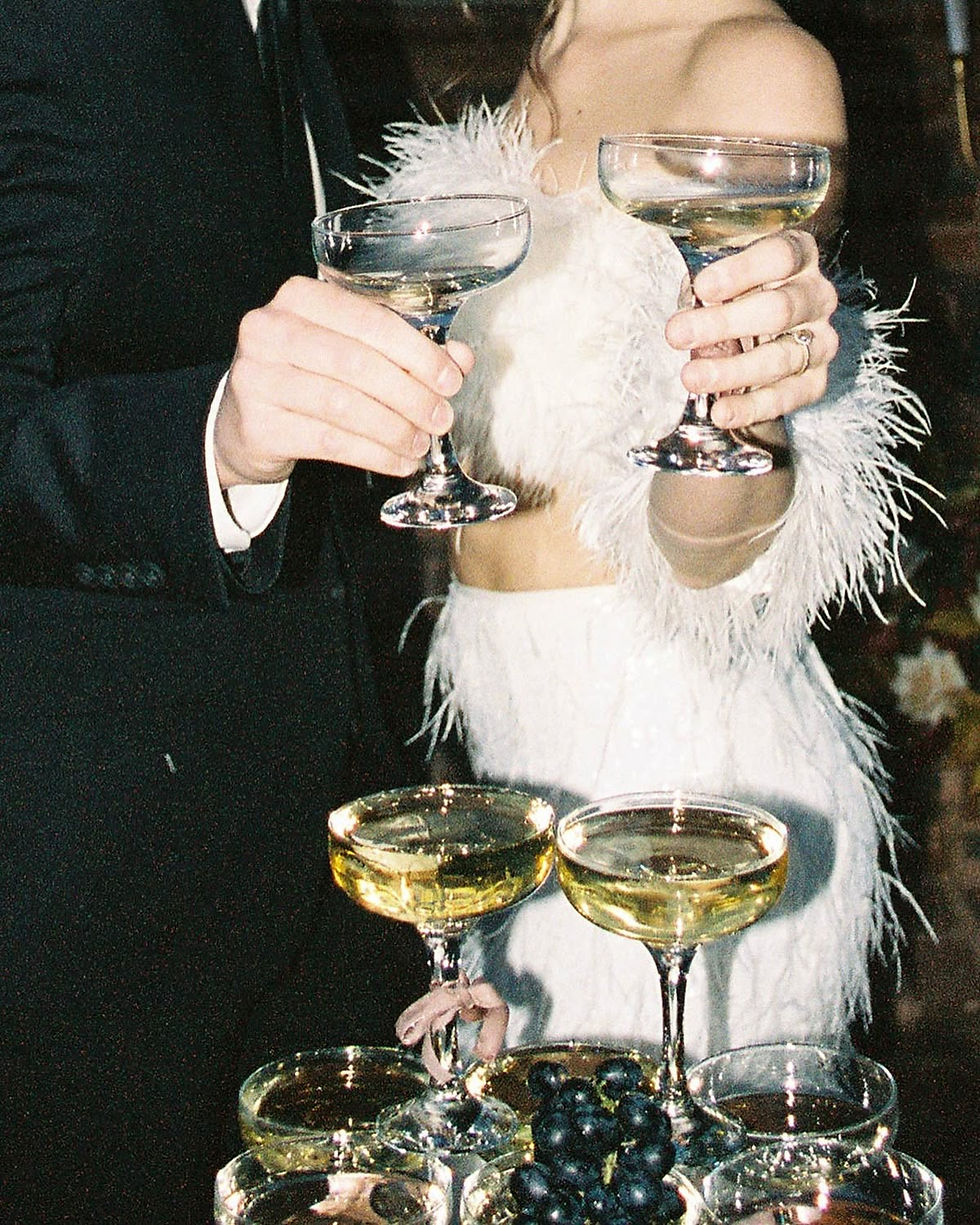 20s inspired couple cheersing champagne glasses over a champagne tower