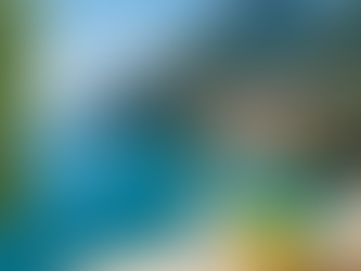 Mediterranean coastal view with turquoise water, Italian cliffside town, and a glass of sparkling water with fresh lemons on a stone balcony