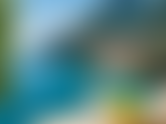 Mediterranean coastal view with turquoise water, Italian cliffside town, and a glass of sparkling water with fresh lemons on a stone balcony