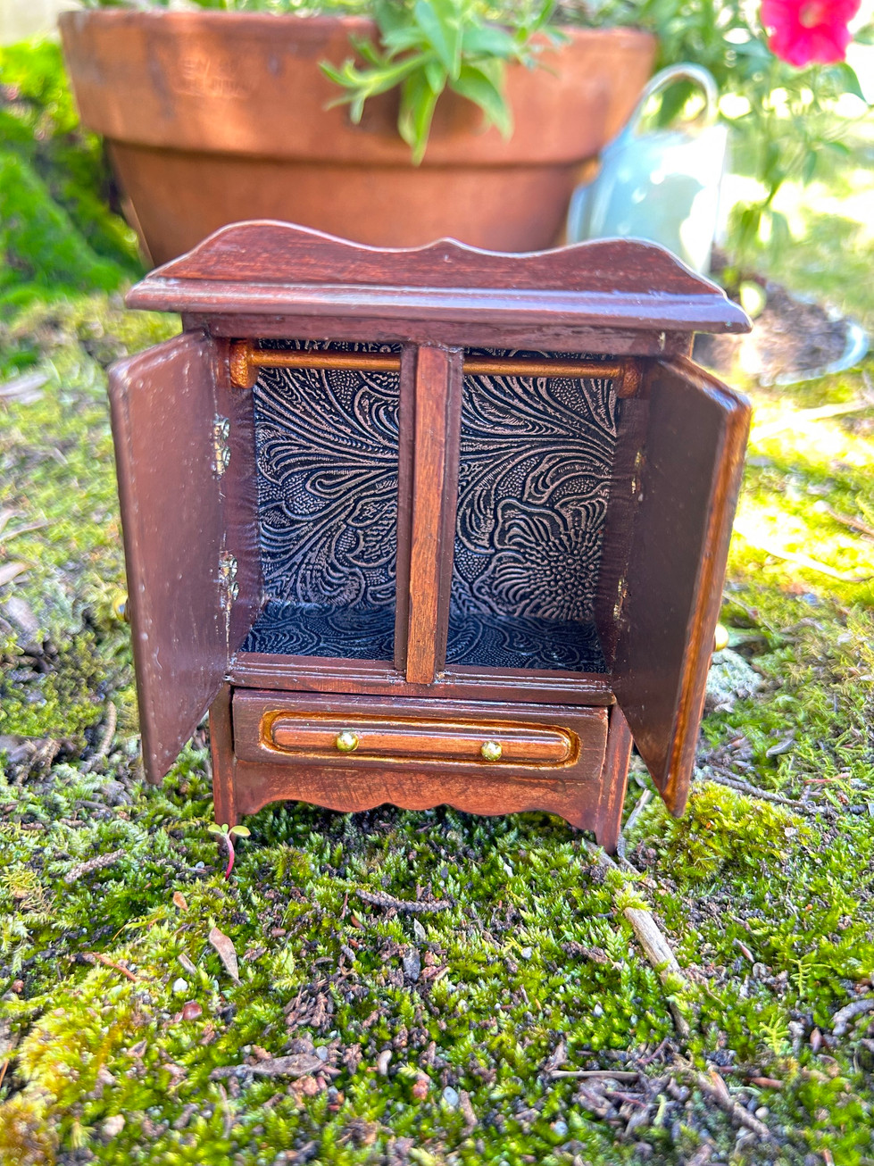 a small wooden cabinet with a drawer sits on a mossy surface