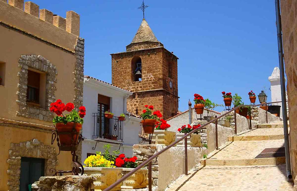 Calle empedrada con flores y vista al campanario
