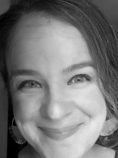 Close-up image of the face of a smiling white woman with side-parted brown hair.