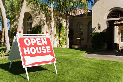 A Tucson home's front lawn with palm trees and a decorative fountain, framed by an “Open House” sign pointing toward the entrance. The well-kept exterior and sunny backdrop suggest a freshly cleaned space ready to welcome potential buyers.