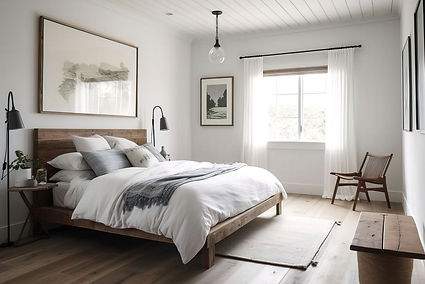 A clean, modern Tucson bedroom with white walls, soft wood floors, and natural light streaming through sheer curtains. A simple wooden bed frame with crisp white bedding and gray accents anchors the space, complemented by warm touches like a woven chair, minimalist pendant light, and polished side table—ideal for showcasing the comfort and clarity that professional home cleaning brings.