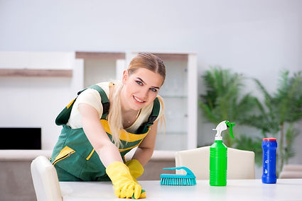 A Tucson home receiving a one-time cleaning, with a person in gloves scrubbing a white surface beside organized cleaning supplies. Plants and a cabinet in the background suggest a routine deep clean to restore order and freshness.