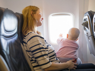 Mom flying with a baby seated by an airplane window