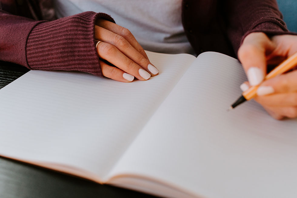 Close up of hands with pink nail polish about to write in blank notebook.